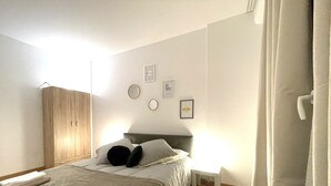 Quarto bem arrumado com cama, mesa de cabeceira e guarda-roupa.