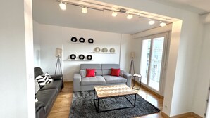 Uma sala de estar moderna com um sofá cinzento, uma mesa de centro e pratos decorativos na parede.