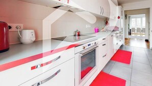 Uma cozinha moderna com armários brancos, bancada vermelha e tapete vermelho.