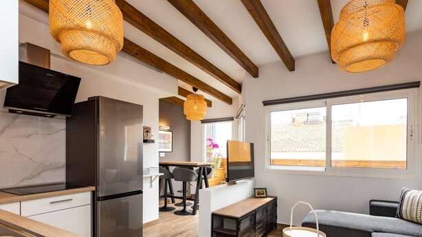Una cocina moderna con refrigerador empotrado, piso de madera y un comedor con mesa y sillas.