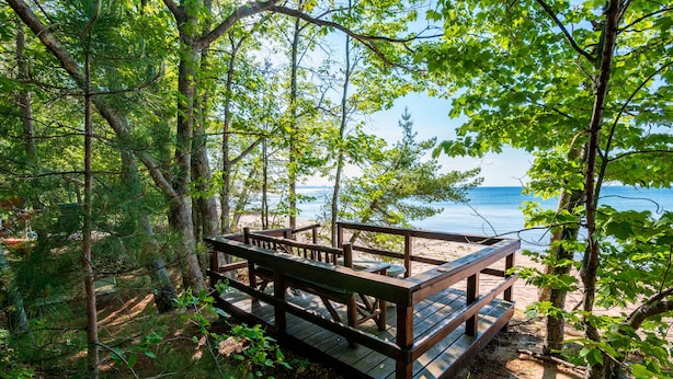 Una terraza de madera con bancos que da a una playa.