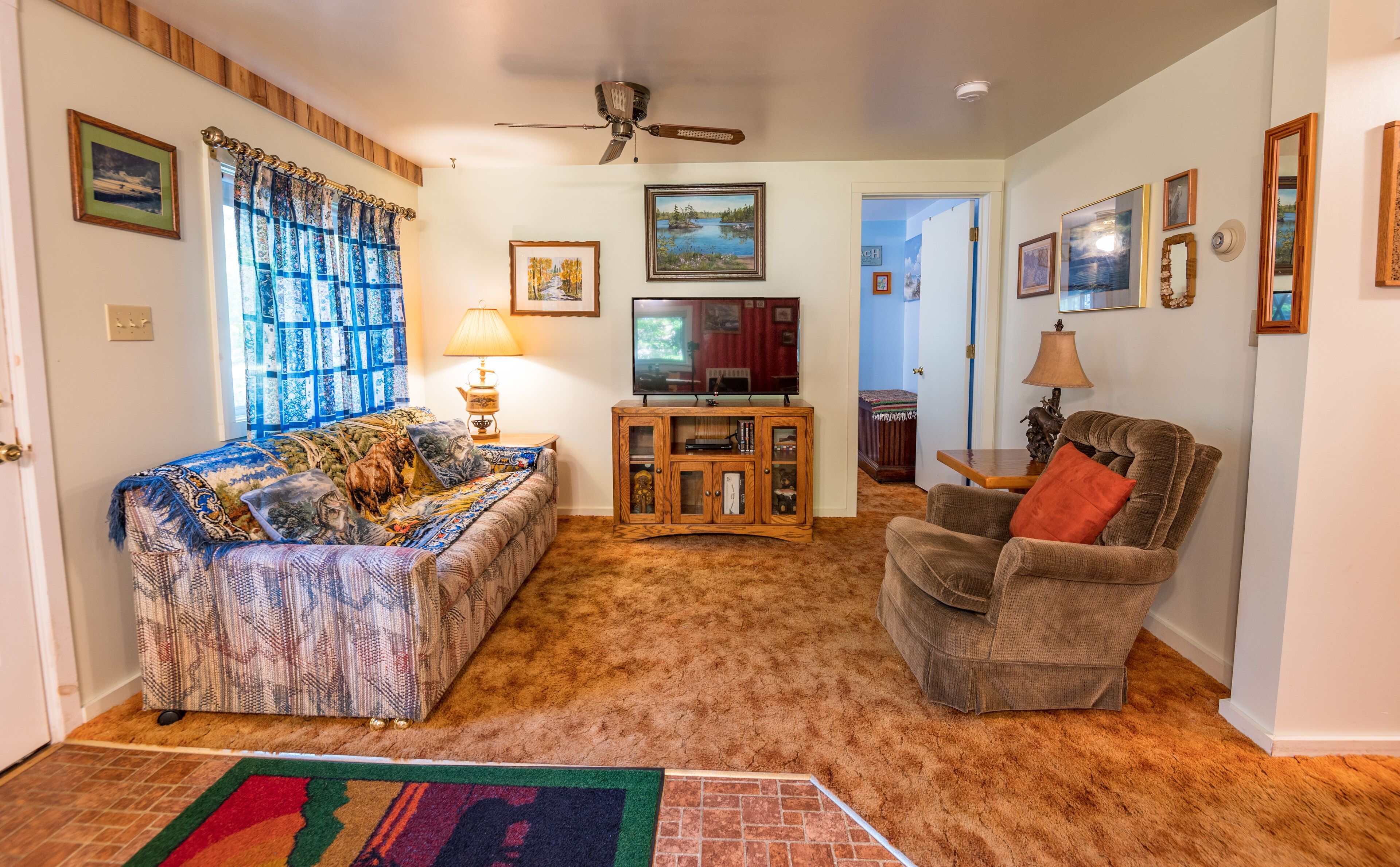 A living room with a sofa, armchair, TV, and a cabinet.