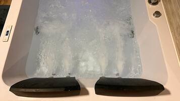 Een bad/douchecombinatie, een bubbelbad, handdoeken