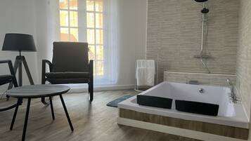 Een bad/douchecombinatie, een bubbelbad, handdoeken