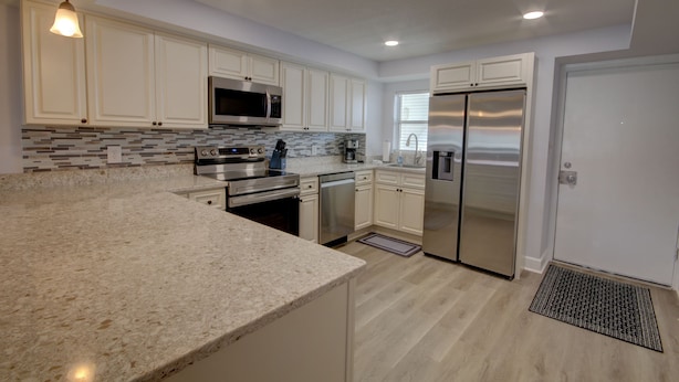 A modern kitchen with white cabinets, stainless steel appliances, and a granite countertop. - El Matador 461 -  FREE TICKETS!! Your stay includes free tickets to many area attractions! (Fort Walton Beach)