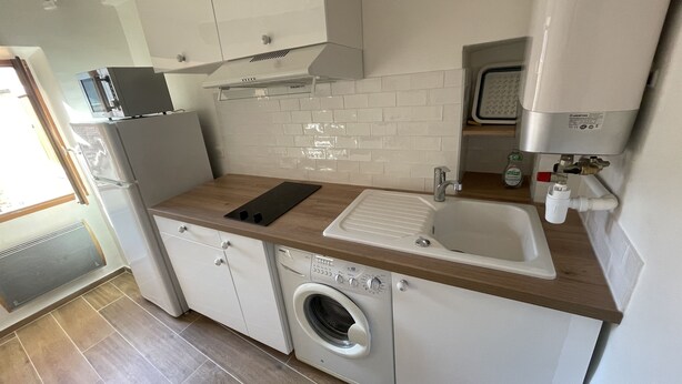 A compact kitchen with a washing machine, a microwave, and a sink. - Charming, relaxing apartment (Sainte Agnès)