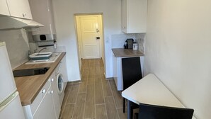 A narrow kitchen with a washing machine, a sink, and a dining area with a table and chairs. - Charming, relaxing apartment (Sainte Agnès)