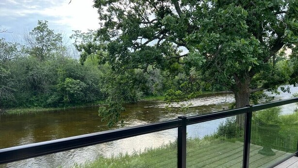 A wooden deck with a glass railing overlooking a river. - Welcome to Blueberry Cottage, a peaceful Oasis (Mississippi Mills)