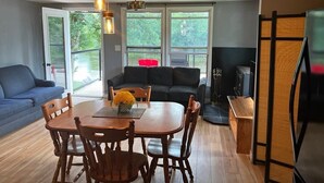 A dining area with a wooden table and chairs, a sofa, and a fireplace. - Welcome to Blueberry Cottage, a peaceful Oasis (Mississippi Mills)