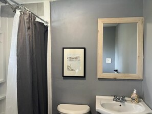 Een bad/douchecombinatie, handdoeken, zeep, toiletpapier