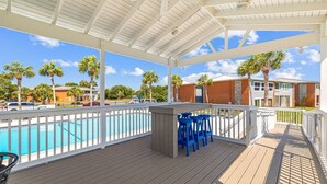 Un espace extérieur abrité comprenant une piscine, un bar et des sièges.