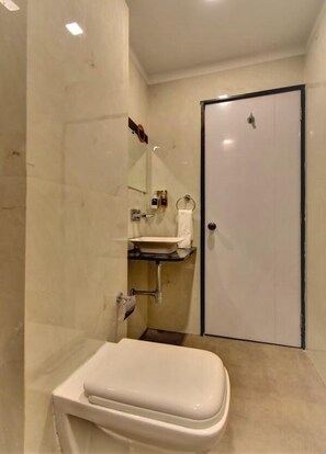 A compact bathroom with a toilet, sink, and shower area. - Manomay (Nagpur)
