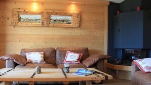 A cozy living room with a wooden sofa set, a wooden coffee table, and a fireplace. - Sunset A 4 by Interhome (Villars)