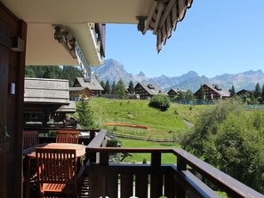 A balcony with wooden railings overlooking a mountainous landscape with traditional wooden houses. - Sunset A 4 by Interhome (Villars)