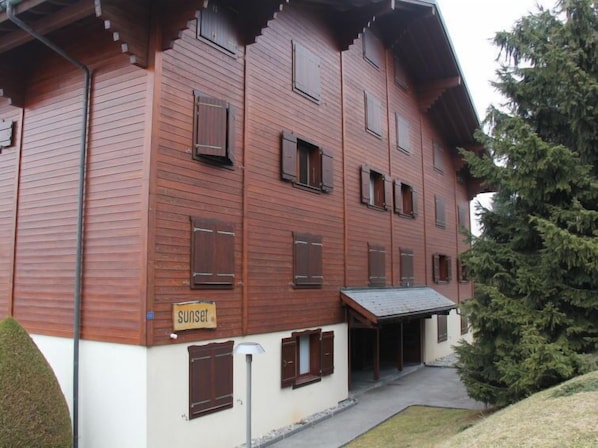 A multi-story wooden building with a sign reading "sunset". - Sunset A 4 by Interhome (Villars)