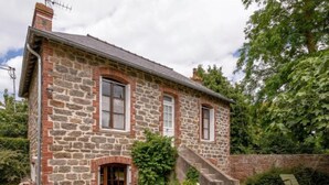 A stone house with a brick chimney, a front door, and a small porch. - Les Tourelles by Interhome (Dinard)