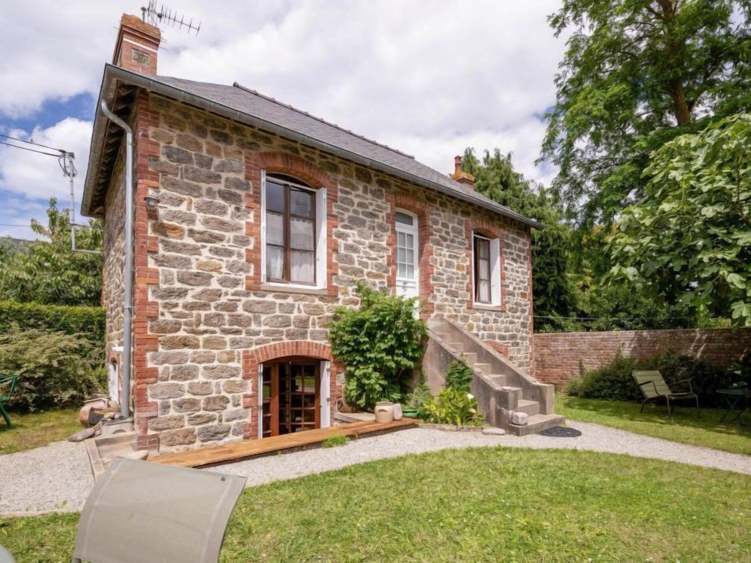 A stone house with a brick entrance, a small porch, and a staircase leading to the upper floor.