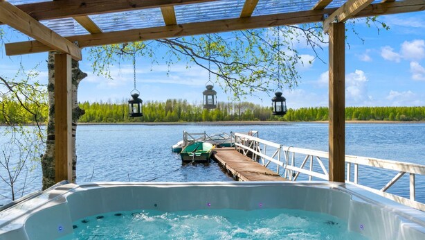 Un jacuzzi con terraza de madera y vista a un muelle con un barco.