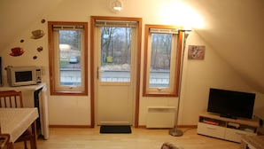 A small, cozy room with a dining table, microwave, television, and a door with windows. - Scandinavian vacation home with sauna by the Baltic Sea (Stove)