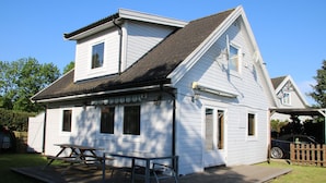 A two-story white house with a covered porch and a picnic table. - Scandinavian vacation home with sauna by the Baltic Sea (Stove)