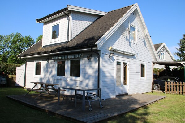 Een wit huis met twee verdiepingen, een overdekte veranda en een picknicktafel.