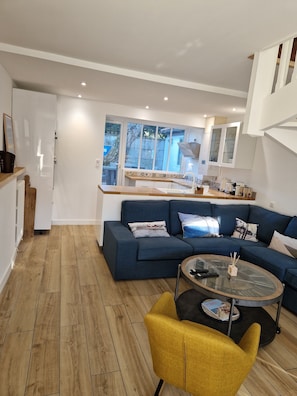 Uma sala de estar moderna com um sofá azul, uma poltrona amarela e uma mesa de centro de vidro.