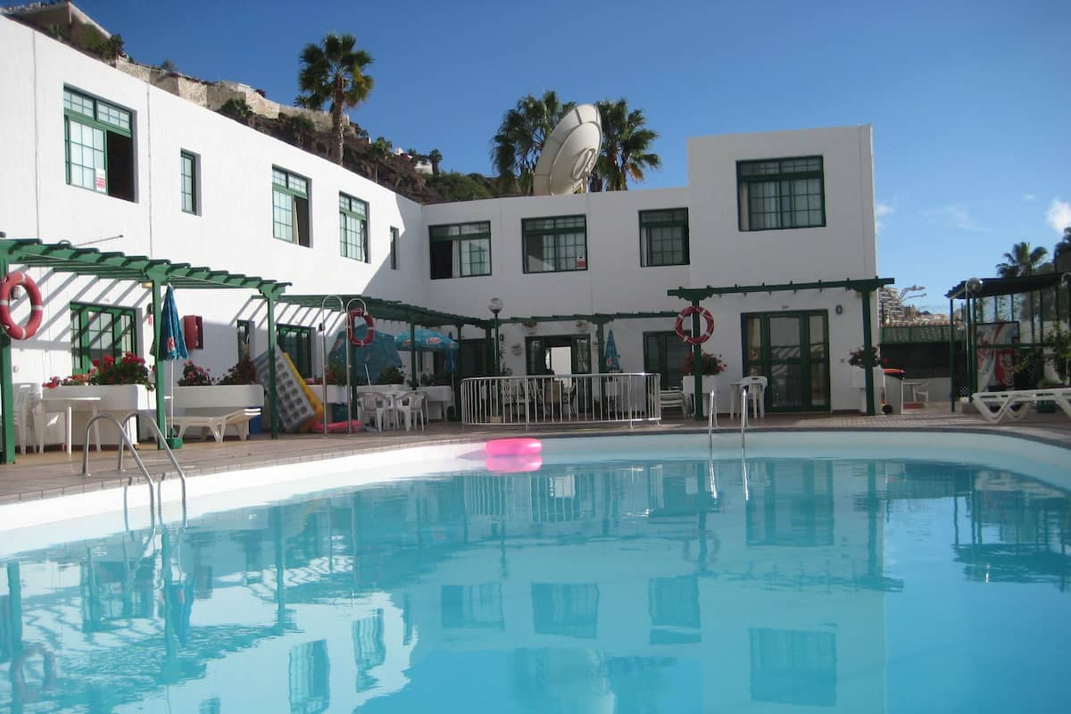 Piscina com escorrega, área de estar externa e boia salva-vidas.