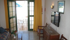 Una stanza con un tavolo da pranzo, sedie, una TV montata a parete e una porta che dà sull'esterno.