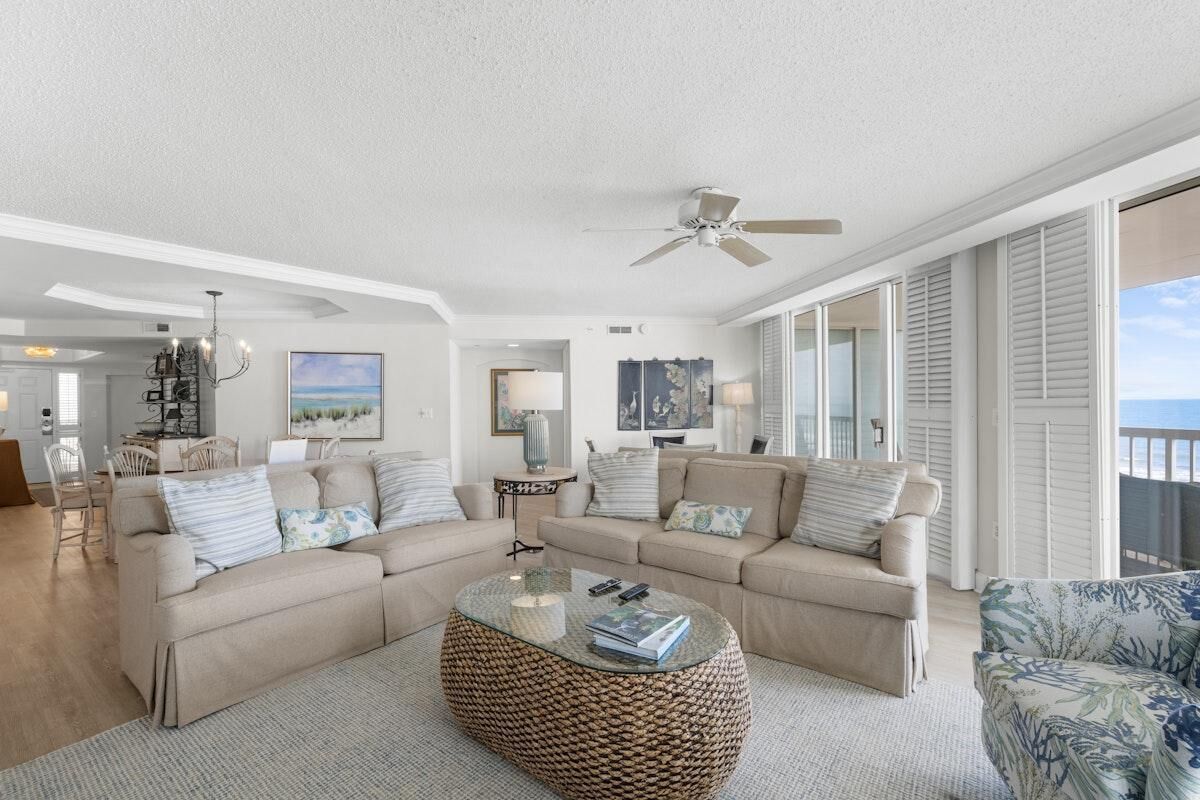 A spacious living room with a large round coffee table, two sofas, and a chair.
