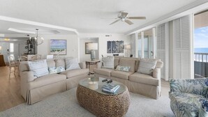 A spacious living room with a large round coffee table, two sofas, and a chair.