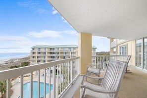 Un balcon avec vue sur une plage et une piscine.