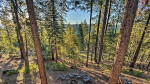 A forest campsite with a fire pit and four Adirondack chairs arranged around it. - Hike, Fish, & Relax: Family Arnold Cabin (Arnold)