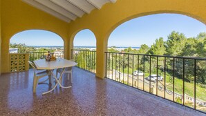 A balcony with a table and chairs, a view of the sea, and a railing. - 014 Villa Colonia (Denia)