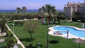 Zona de piscina con diseño curvo, palmeras y vista al mar.