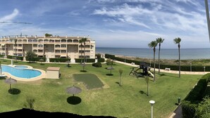 Un hotel con piscina, palmeras y vista al océano.