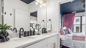 A modern bathroom with a large mirror, black faucets, and a vanity.