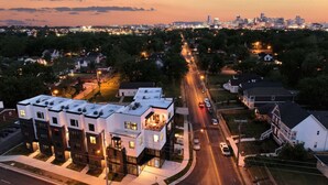 A residential area with modern buildings, a main road, and a distant city skyline.