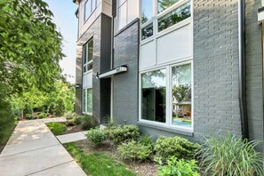 A modern two-story building with a brick facade, large windows, and a well-maintained garden. - Good Vibes Only - Walkable to breweries, cafes, restaurants & close to Broadway (Nashville)