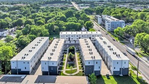 Monikerroksinen hotelli, jossa on keskeinen sisäpiha, ja sen ympärillä on vehreää kasvillisuutta ja avoin taivas.