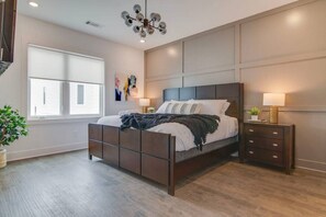 A modern bedroom with a large bed, bedside tables, a chandelier, and a window. - Good Vibes Only - Walkable to breweries, cafes, restaurants & close to Broadway (Nashville)