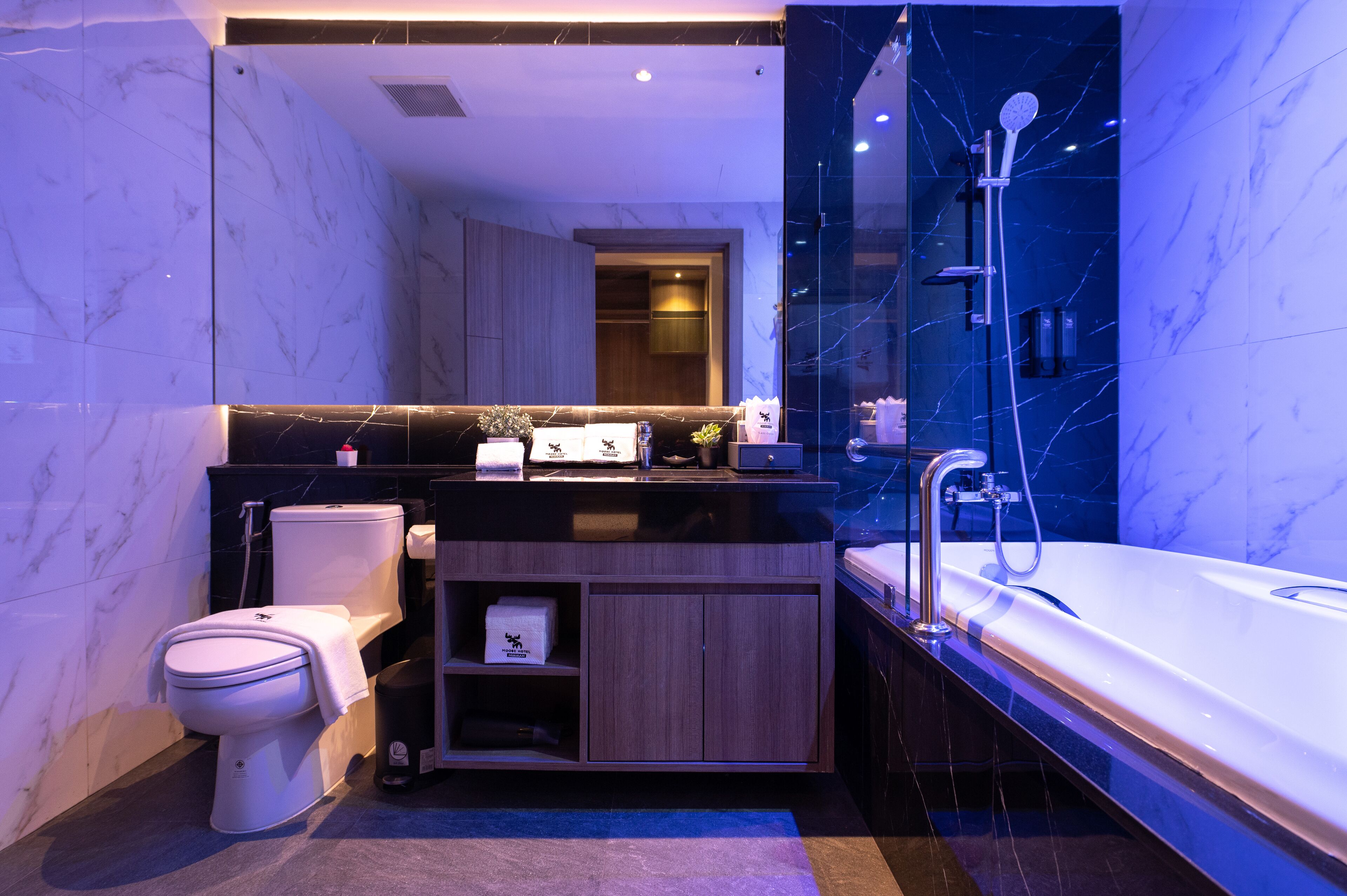 A modern bathroom with a marble vanity, a toilet, a bathtub, and a shower.