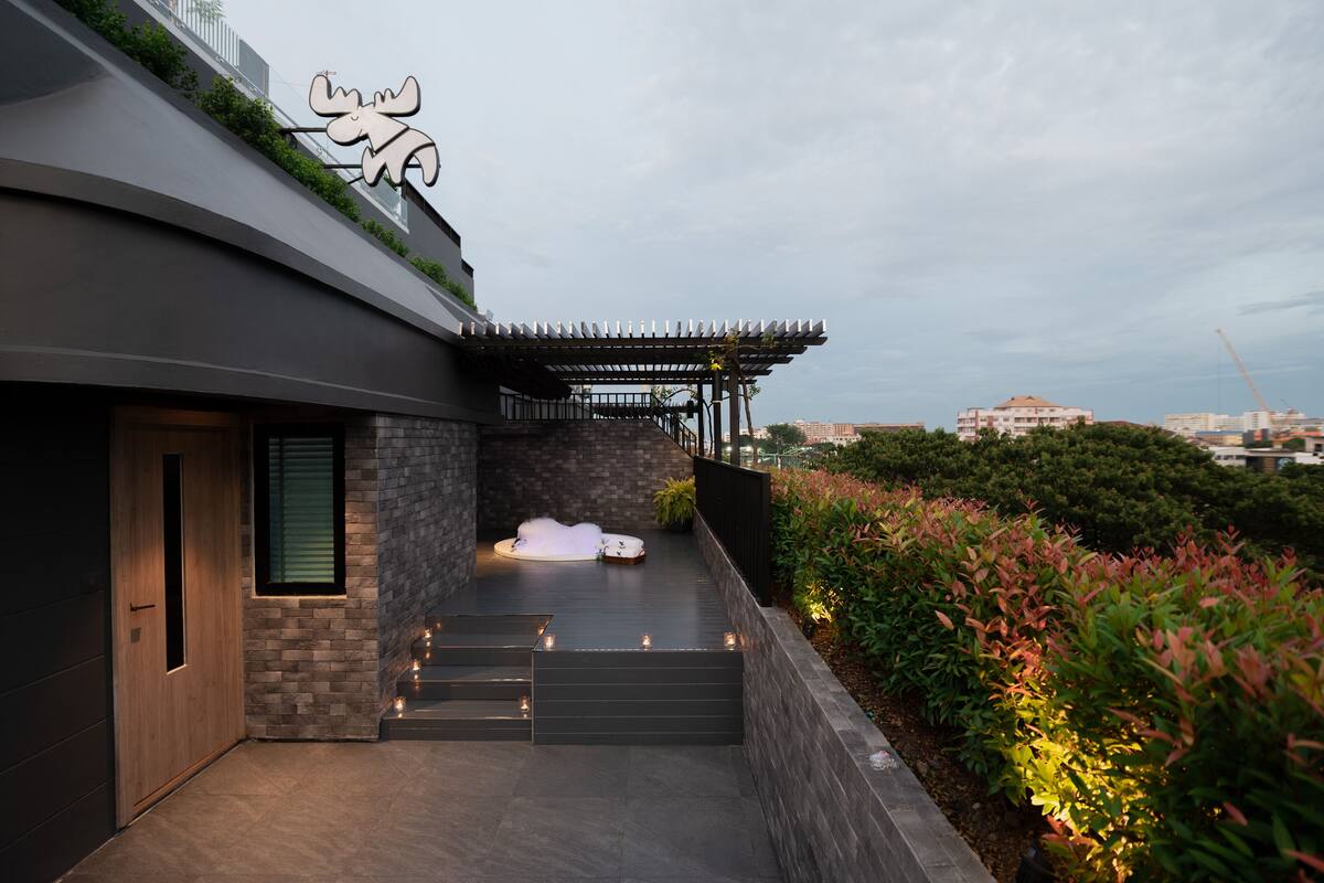 A modern building with a unique moose logo, a stone facade, and a rooftop garden with steps leading to a seating area.