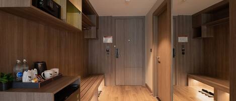 A modern hotel corridor with wooden flooring, built-in shelving, and a coffee station.