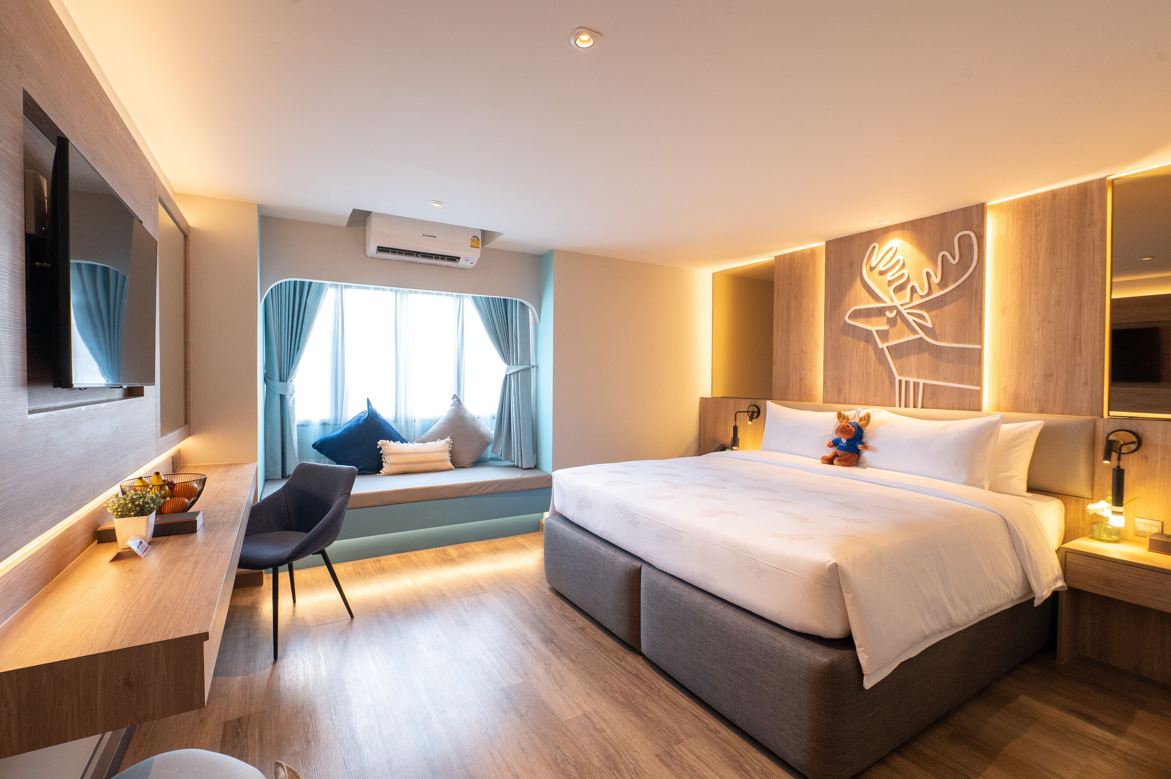 A modern hotel room with a large bed, a desk, a chair, and a window with curtains.