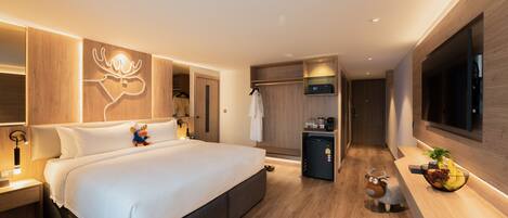 Habitación de hotel moderna con una cama grande, un refrigerador pequeño, un televisor y un diseño de pared de madera.