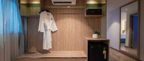 A modern bathroom with a wooden vanity, a towel rack, a small refrigerator, and a bench.