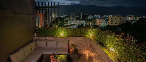 A rooftop terrace with a sofa, two tables, and a potted plant.