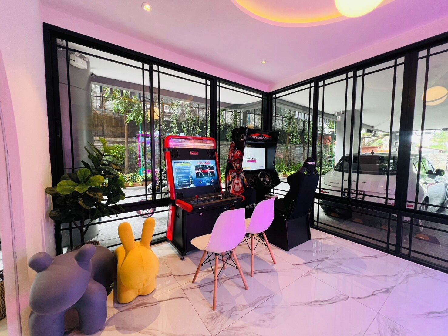Een speelruimte met twee gokautomaten, een knuffel en een zithoek met stoelen.