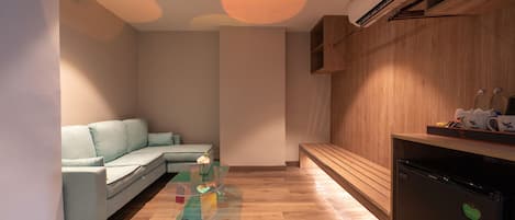 A modern living room with a sectional sofa, a glass coffee table, and a wooden bench.