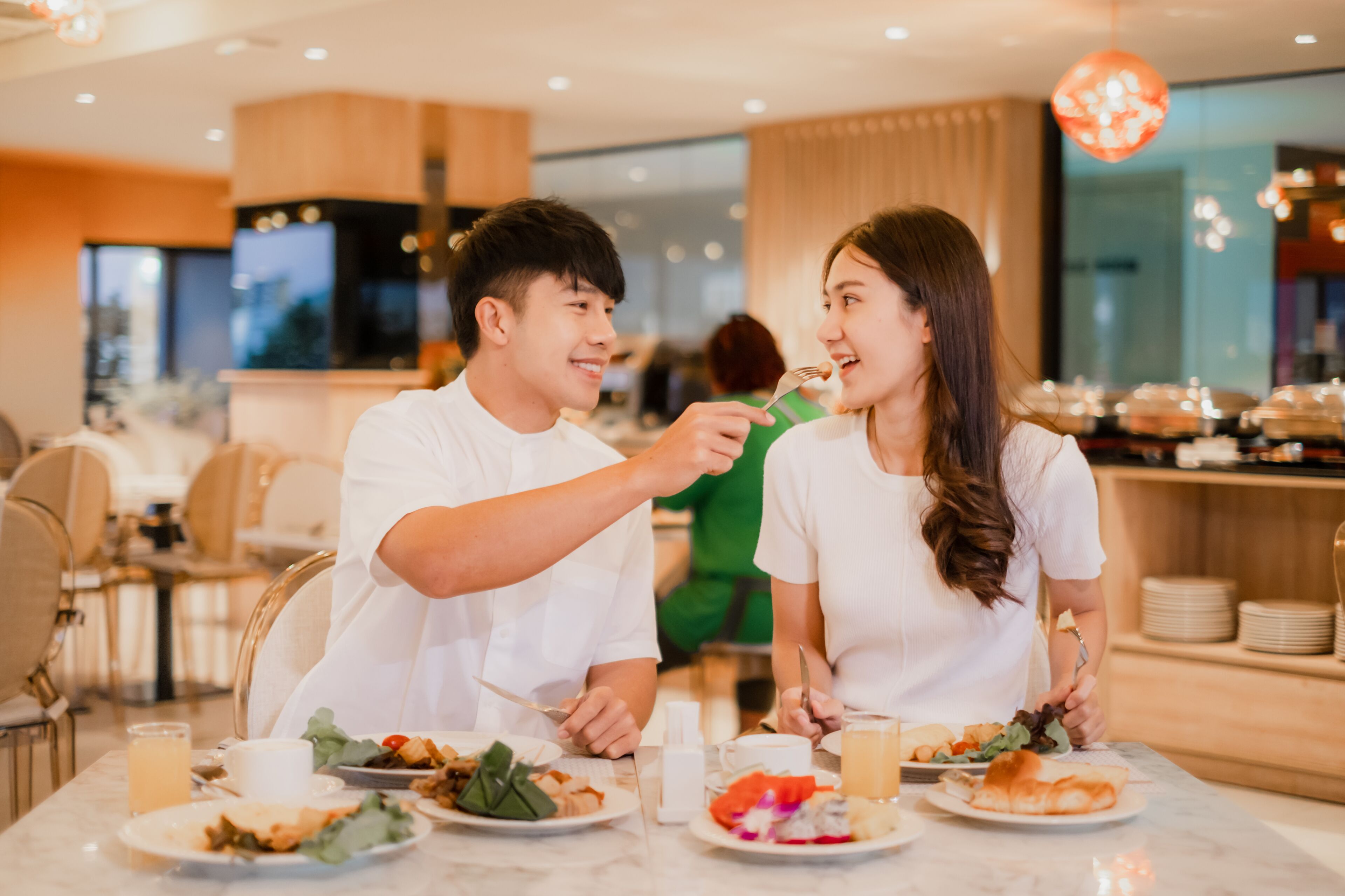 A couple dining at a restaurant with a modern interior, including a marble table and contemporary lighting.